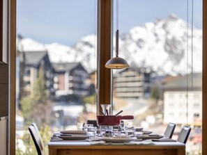 Una mesa de comedor dispuesta con platos, vasos y cubiertos, con una vista de montaña al fondo.