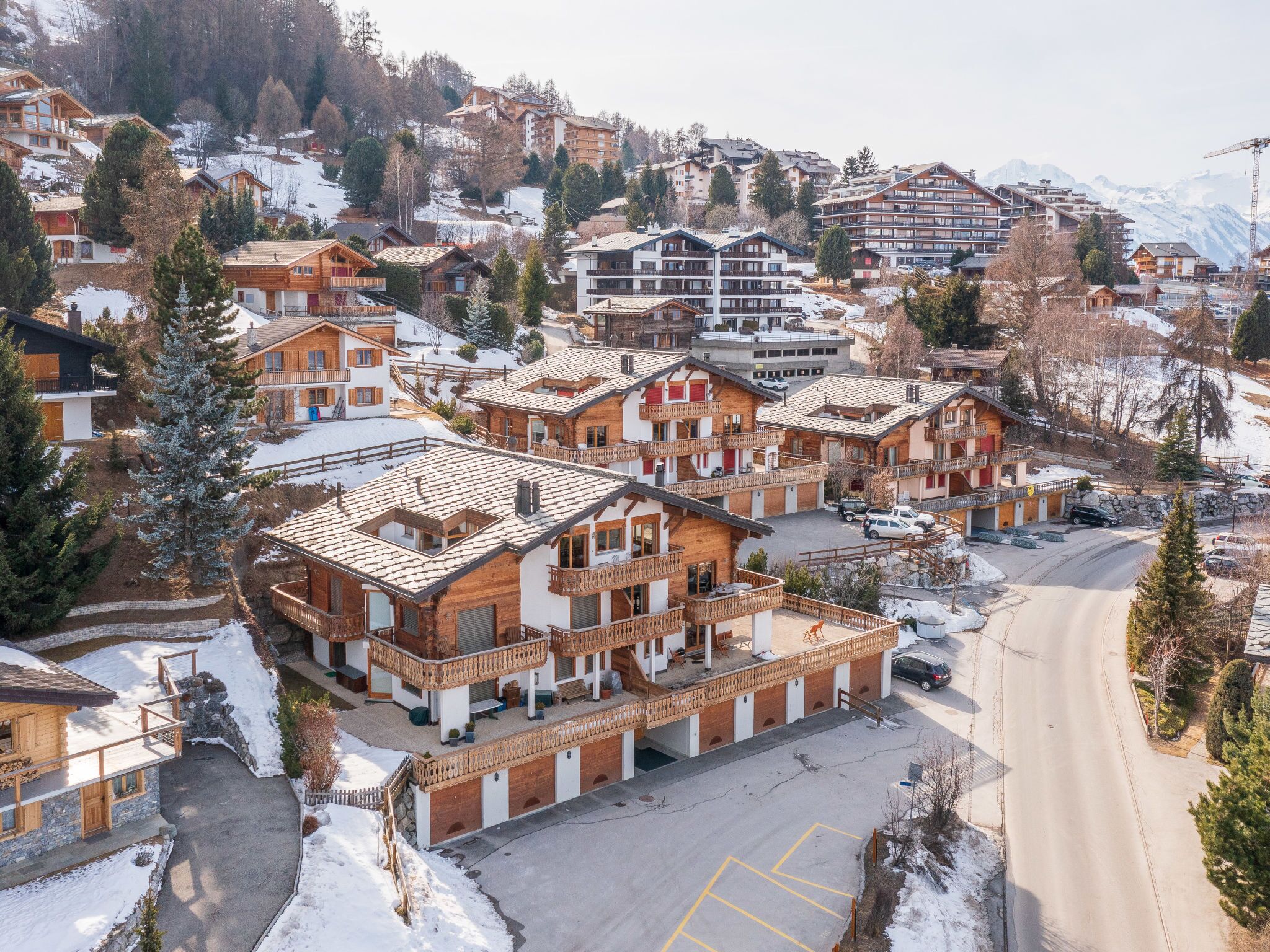 A ski resort with chalet-style buildings, a parking area, and a mountain backdrop.