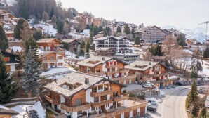 Une station de ski avec des bâtiments de style chalet, un parking et un paysage montagneux en toile de fond.