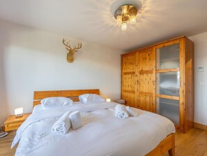 Un dormitorio con una cama de madera, un armario de madera y una cabeza de ciervo montada en la pared.