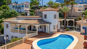 Eine Villa mit Swimmingpool, überdachter Terrasse und Bergblick.