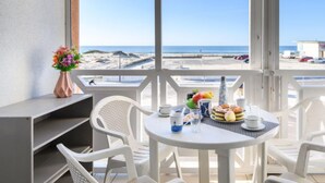 Un balcón con mesa lista para el desayuno, con vista a la playa.