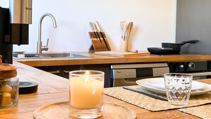 A kitchen with a wooden countertop, a lit candle, a glass candle holder, a knife block, and a stove. - Manui Swimming Pool Condo with Sea & Moorea views (Puna'auia)