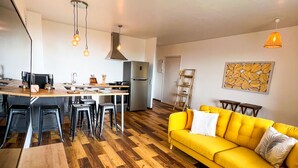 A modern kitchen with a dining area, a yellow sofa, and a wooden floor. - Manui Swimming Pool Condo with Sea & Moorea views (Puna'auia)