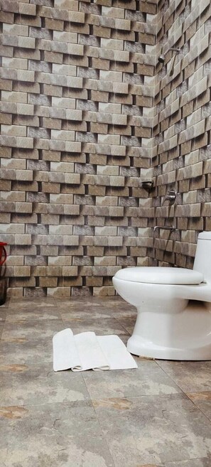 A bathroom with a stone wall and a white toilet. - Corbett Hunters (Previously known as Taarini Corbett) (Salt)