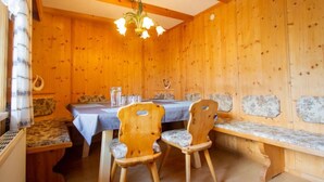 A wooden interior with a dining table, two chairs, a bench, and a chandelier. - Plattner by Interhome (Ötz)