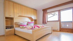 A bedroom with a bed, wooden wardrobe, and a window with a view. - Plattner by Interhome (Ötz)