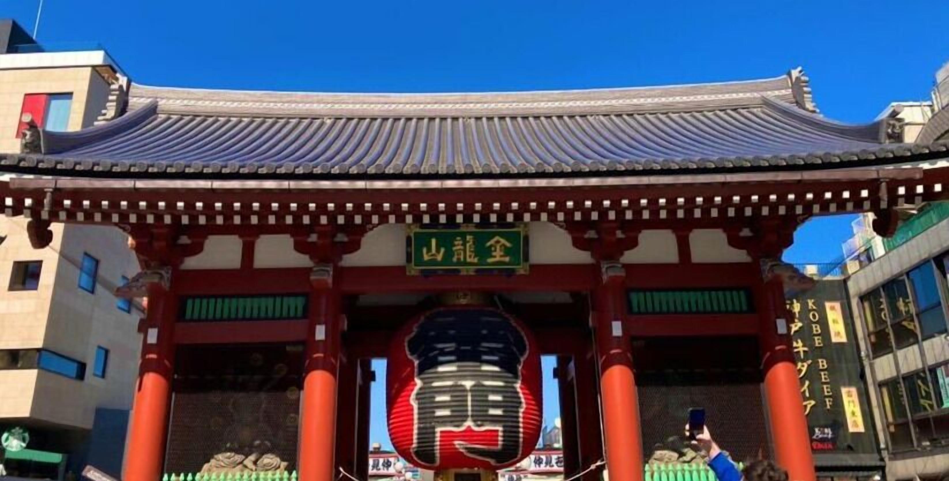 A traditional Japanese gate with a curved roof and red pillars.
