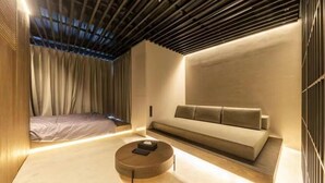 A modern room with a bed, a sofa, and a round coffee table. - AMANECER HOTEL (Tokyo)