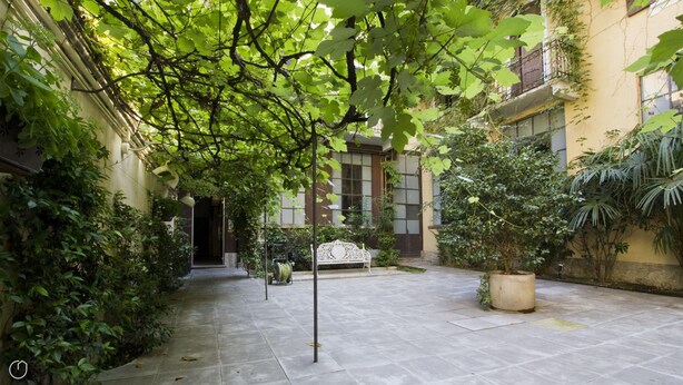 A courtyard with a bench, potted plants, and a building with large windows. - Italianway Easy - Caretto 4 - Toscanini (Milan)
