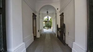 A corridor with white walls, a tiled floor, and an arched ceiling. There is a door on the right and a window at the end of the corridor. - Italianway Easy - Caretto 4 - Toscanini (Milan)