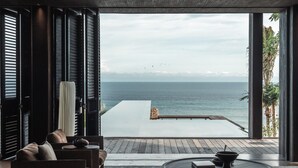 A modern living room with a view of the sea, featuring a sofa, a coffee table, and a large window. - Tampah Hills (Kuta)