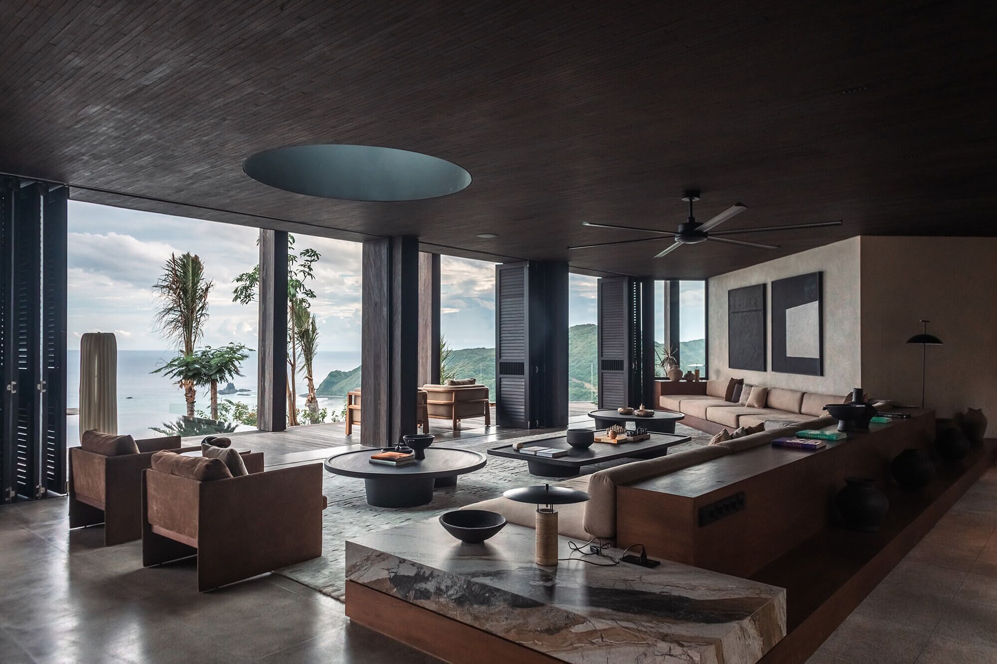 Amplia sala de estar con un gran ventanal con vistas panorámicas, ventilador de techo y muebles modernos.