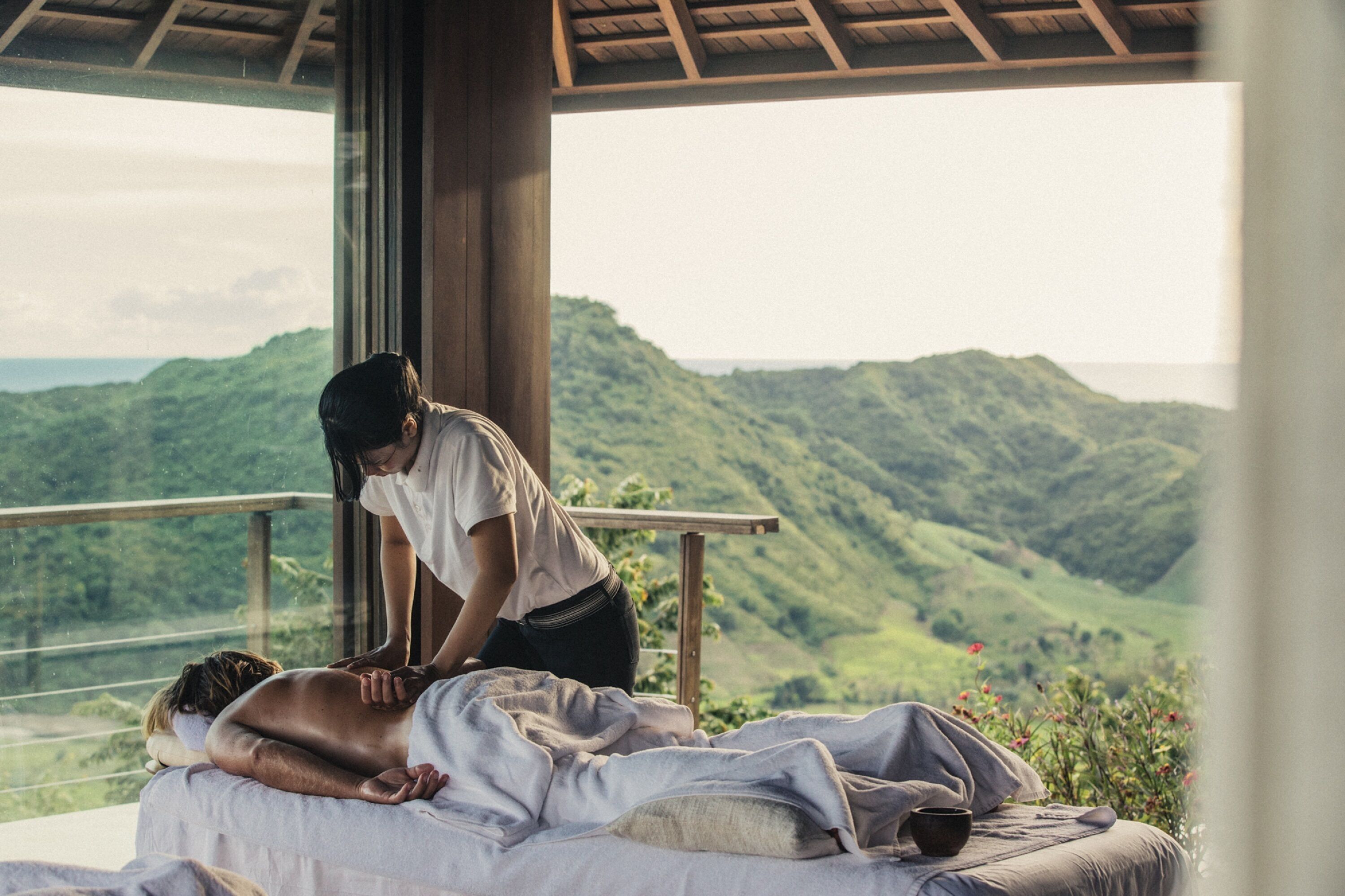 A massage therapy session on a balcony overlooking a mountainous landscape.
