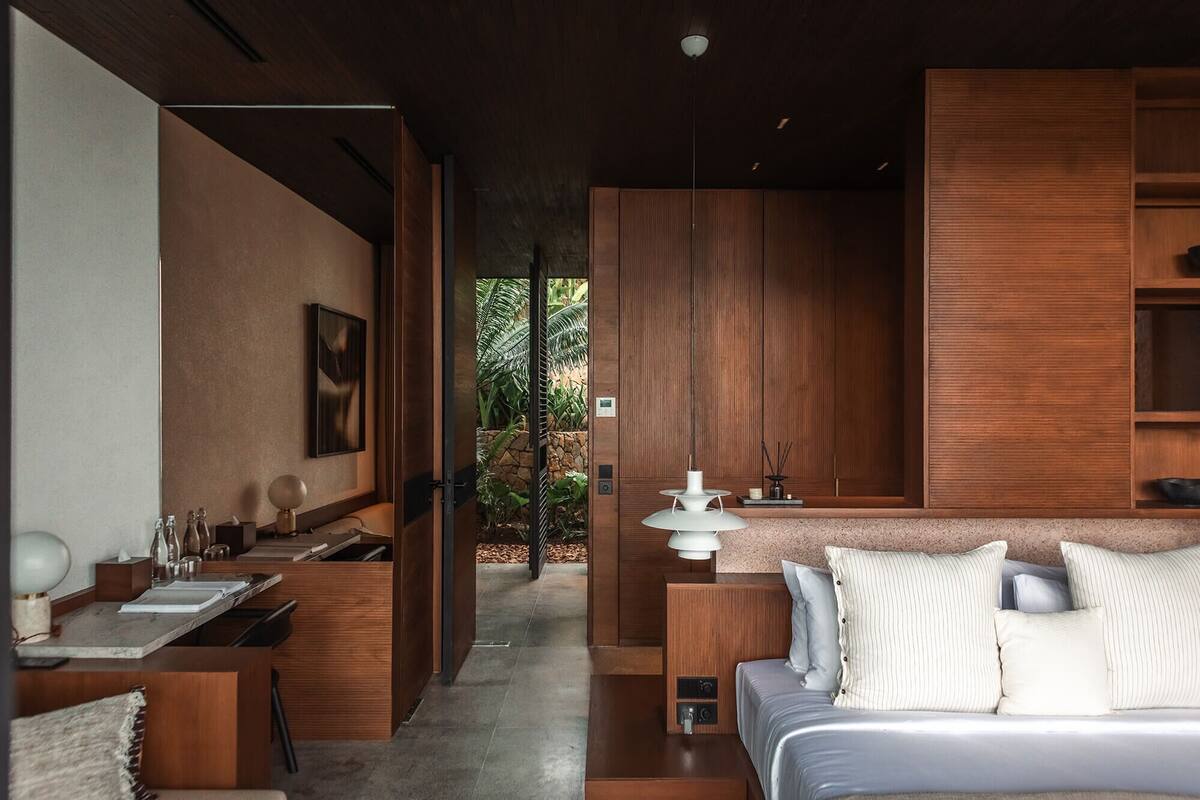 A modern bedroom with a bed, bedside tables, a desk, and a bathroom.