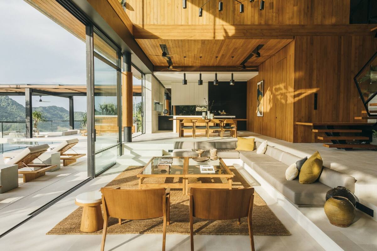 A modern interior with a large glass wall, wooden ceiling, and a dining area with a central table and chairs.