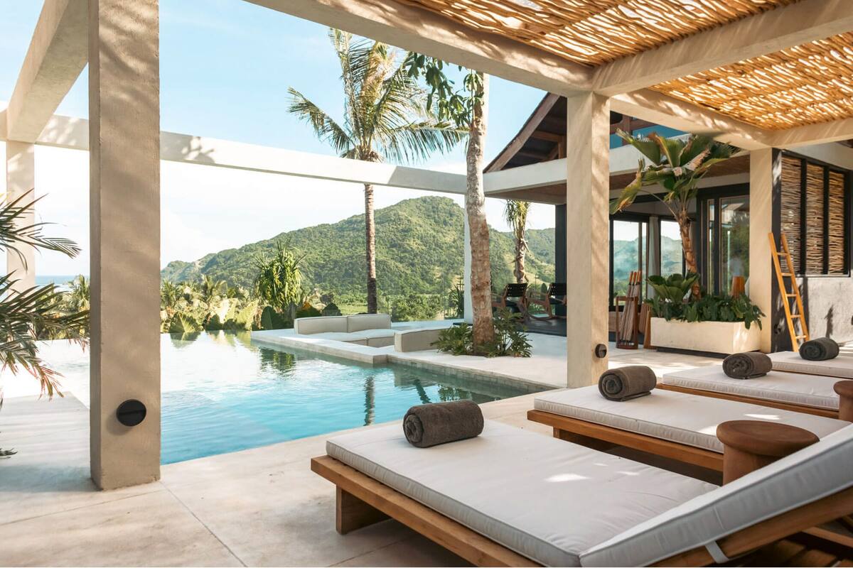 A modern pool area with lounge chairs and a view of a mountain landscape.