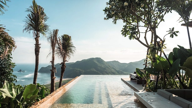 A clear view of a swimming pool with a mountain backdrop, surrounded by lush greenery and palm trees. - Tampah Hills (Kuta)