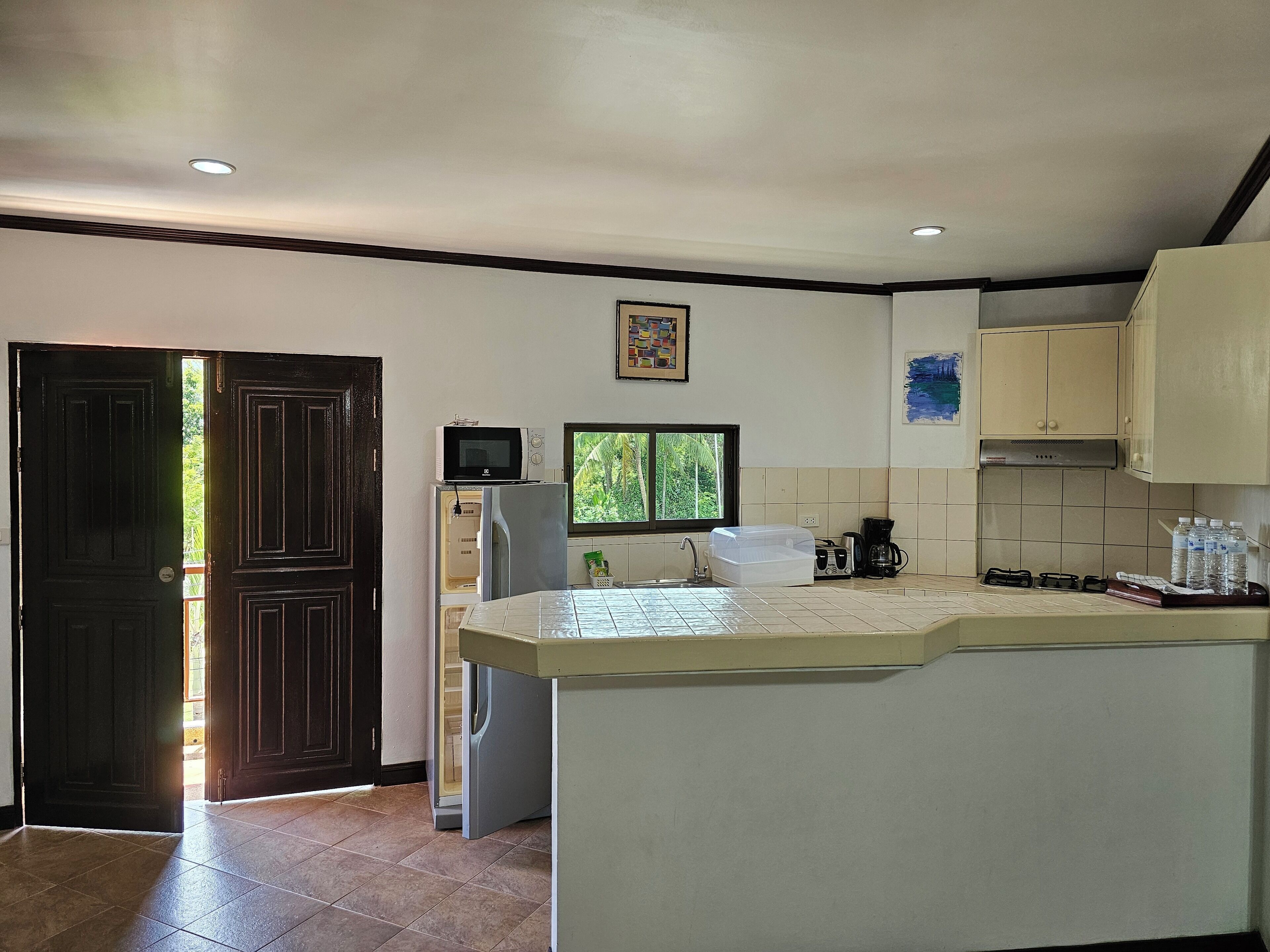 Una cocina con microondas, refrigerador y ventana.