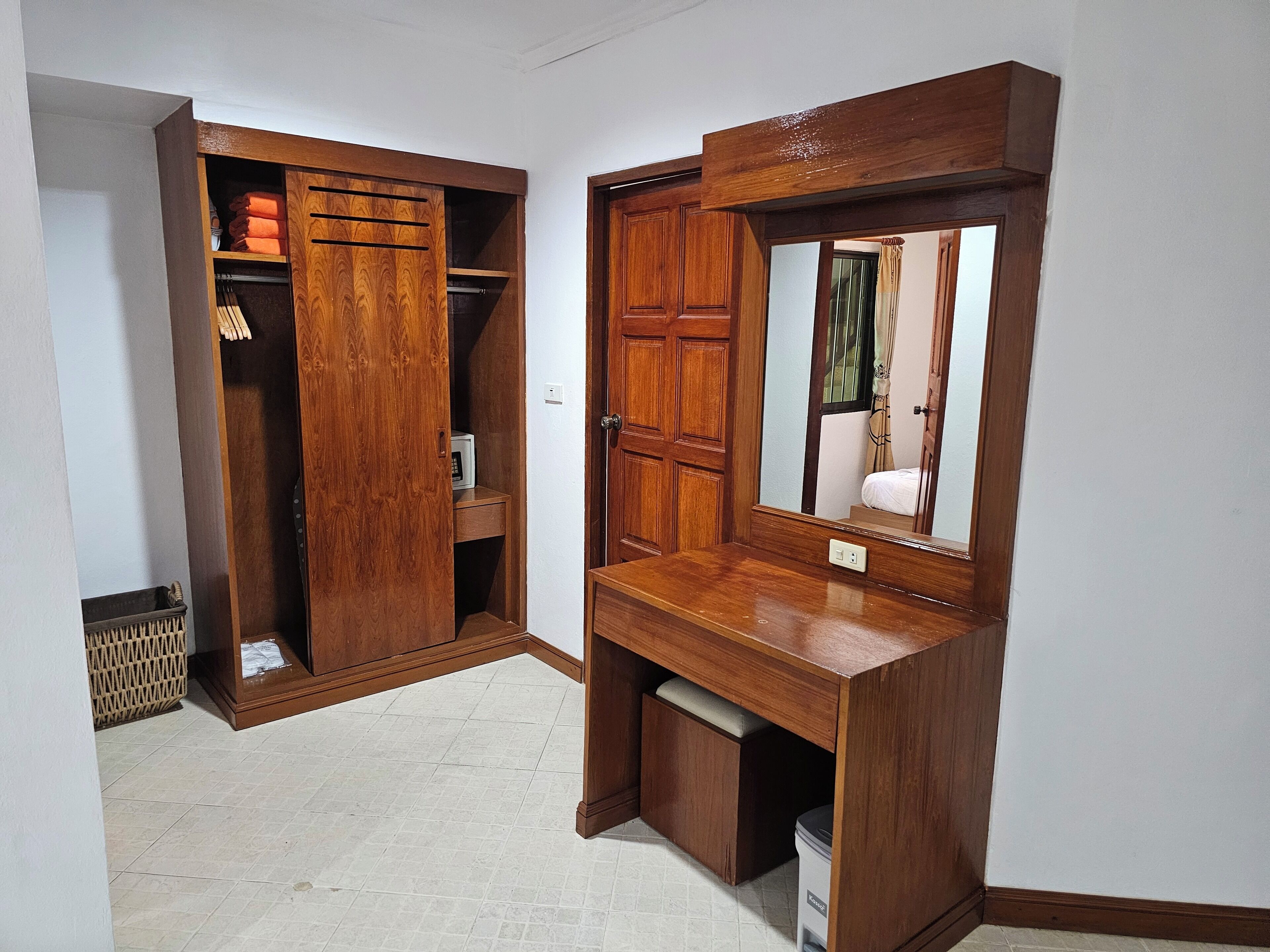 Un armario de madera con espejo y un pequeño escritorio.