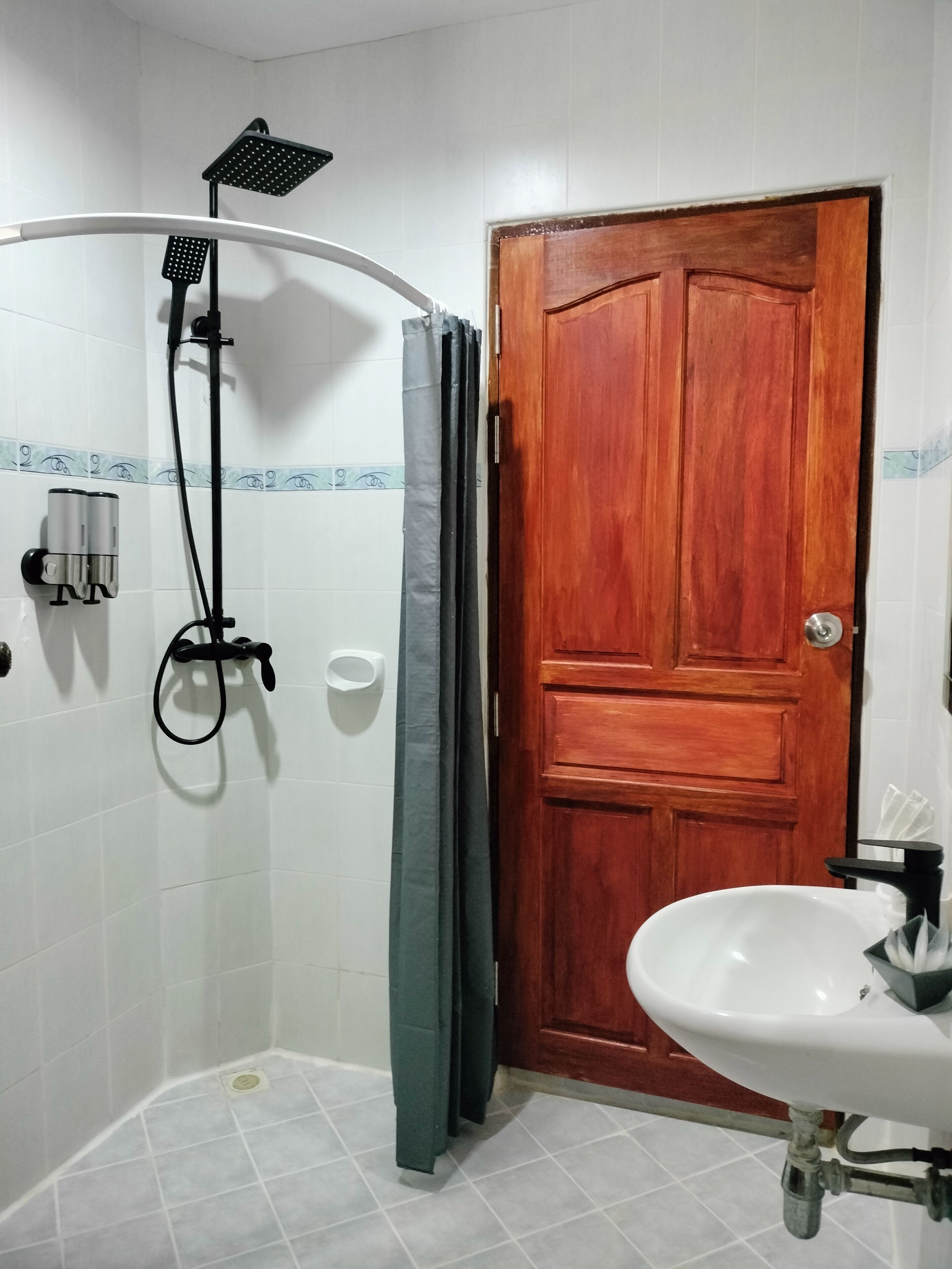 Un baño con ducha, puerta de madera y lavabo.