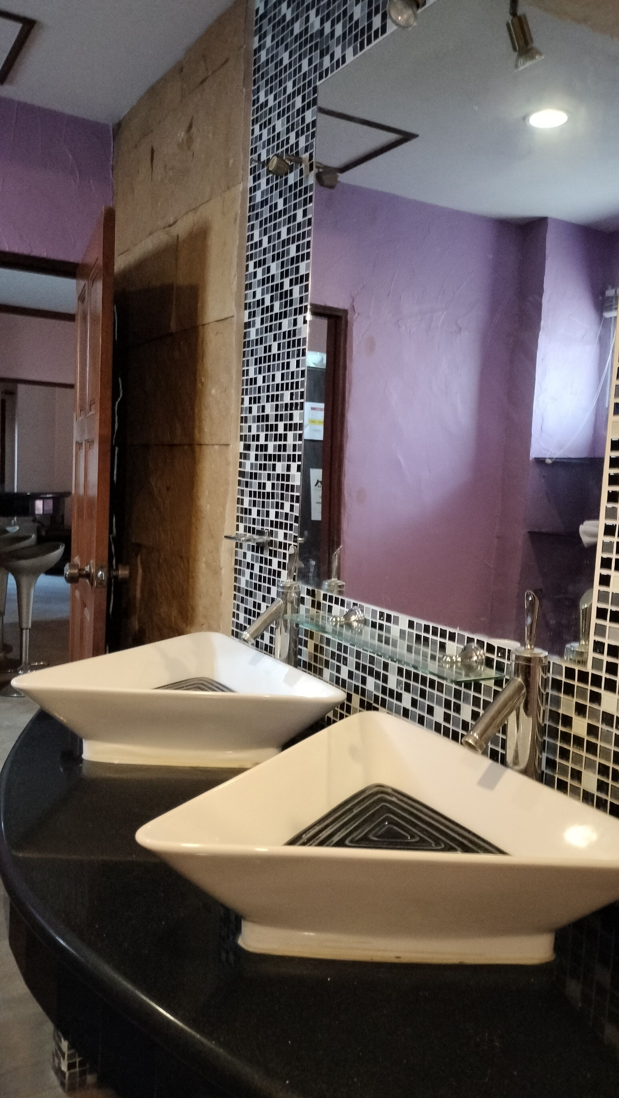 A bathroom with two sinks, a tiled backsplash, and a mirror.