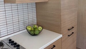 Une cuisine avec des meubles de rangement en bois, un plan de travail blanc et un saladier rempli de pommes vertes.