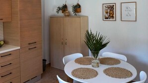 Un espace repas avec une table ronde, des chaises blanches et un luminaire suspendu.