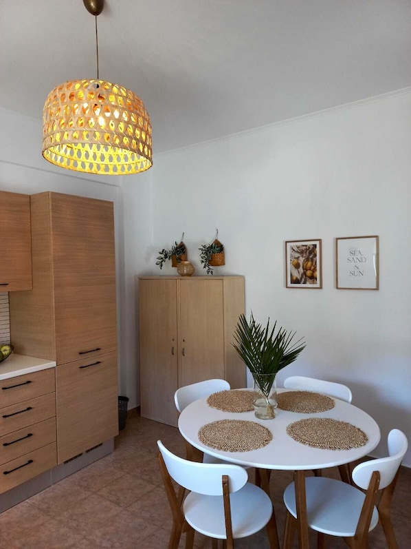Un espace repas avec une table ronde, des chaises blanches et un luminaire suspendu.