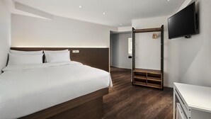 A modern hotel room with a large bed, a TV mounted on the wall, and a wooden floor.