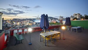 A rooftop terrace with outdoor seating, a table, and umbrellas.