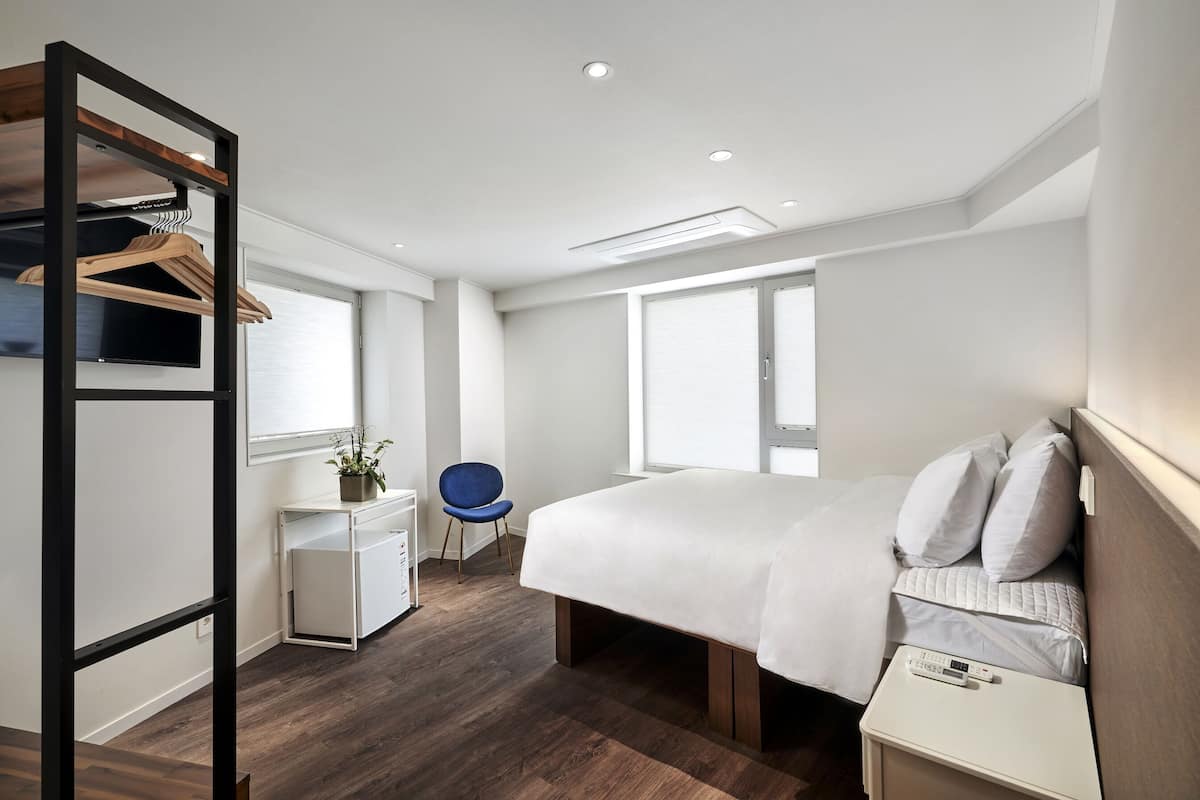 Habitación de hotel moderna con una cama grande, un escritorio, una silla y un armario.