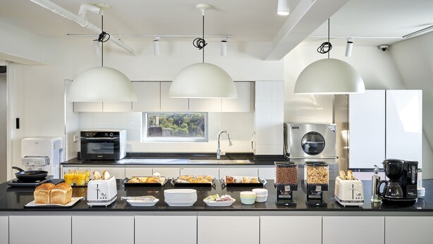 A modern kitchen with a central island, built-in appliances, and pendant lighting.