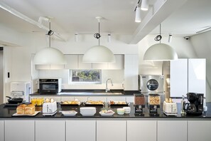 A modern kitchen with a central island, built-in appliances, and pendant lighting. - H HOSTEL Itaewon (Seoul)