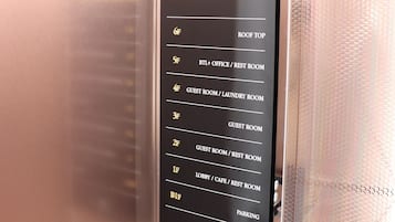 A hotel elevator with a floor information panel listing various rooms and amenities.