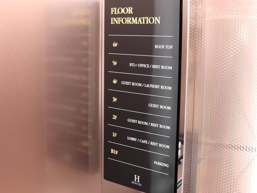 A hotel elevator with a floor information panel listing various rooms and amenities.