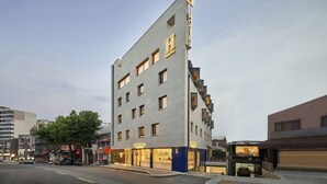 A modern hotel with a prominent 'HOSTEL' sign, multiple floors, and a ground-level storefront.