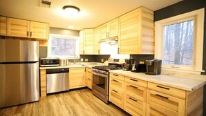 Een moderne keuken met houten kastjes, roestvrijstalen apparatuur en een groot raam.