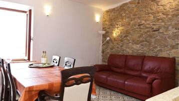 Ein Essbereich mit Holztisch und -stühlen, einer roten Ledersofa und einer Steinwand.