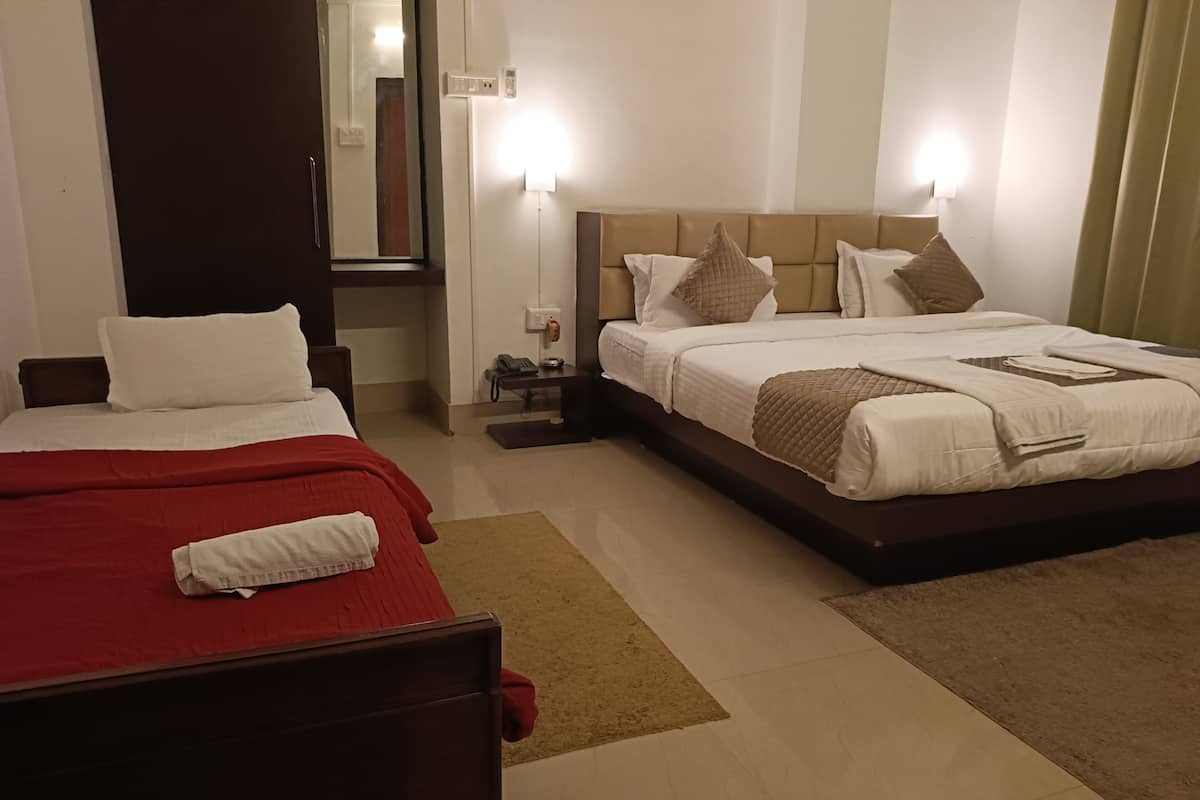 A hotel room with two beds, a bedside table, a mirror, and a wall-mounted phone.