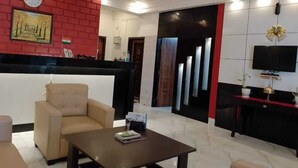 Un vestíbulo de hotel moderno con un mostrador de recepción, una zona de estar y una televisión.