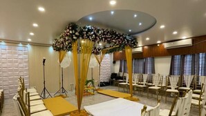 Un salón de banquetes con mesas redondas, sillas doradas y un centro de mesa floral.