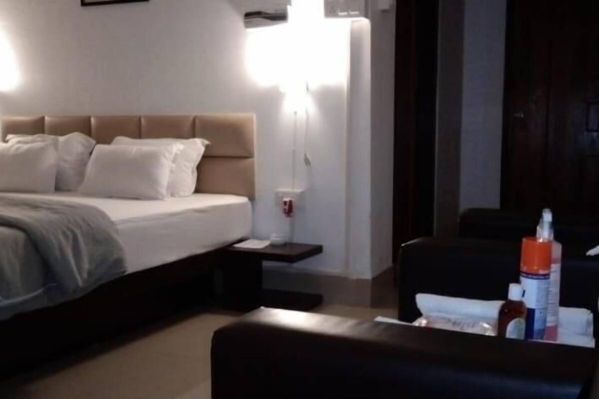 A hotel room with a bed, bedside table, and a chair.