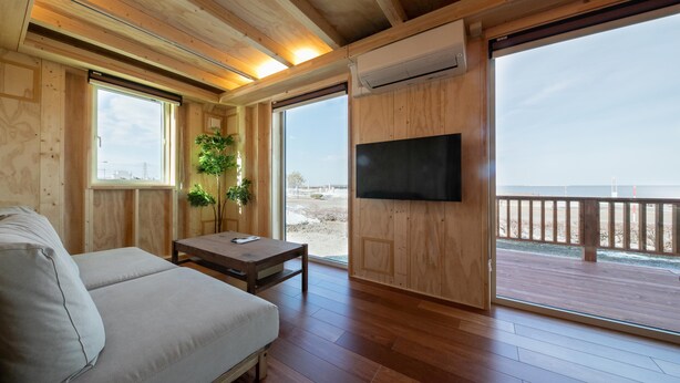 Una baita in legno con divano, tavolo e televisione. Dispone di ampie finestre e vista sulla spiaggia.