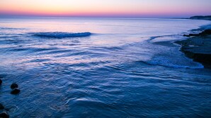 Paesaggio costiero con mare calmo e tramonto.