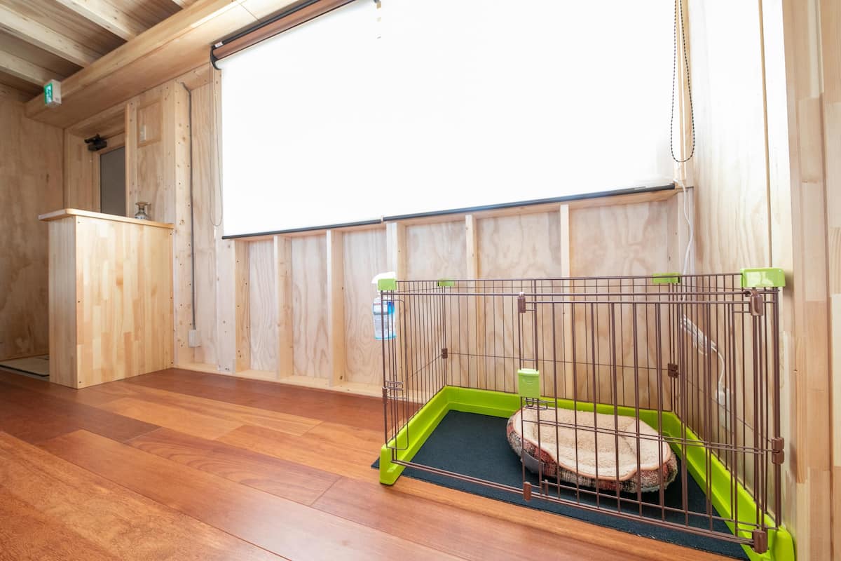 A room with a wooden floor, a green pet cage, and a projector screen on the wall.
