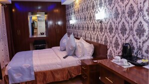 A hotel room with a bed, bedside table, and a mirror. - THE BASE HOTEL (Mbooni)