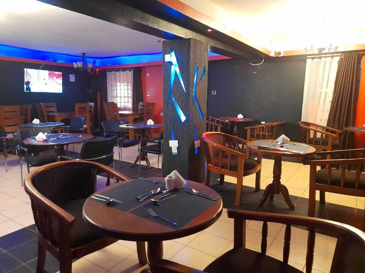 Un restaurante con varias mesas y sillas, algunas con servilletas azules.
