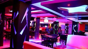 A modern interior with a bar area, seating, and a neon-lit ceiling. - THE BASE HOTEL (Mbooni)