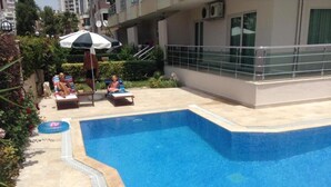 A swimming pool with lounge chairs and an umbrella.